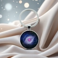 Macro detail of planet glass pendant with nebula pattern on silver silk background - Galaxy Eye