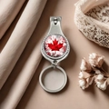 Silver metal nail clipper keychain with red maple leaf design on a silk background - Style 11