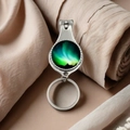 Detail of silver nail clipper keychain featuring a colorful aurora glass dome artwork - Colorful Aurora View