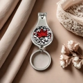 Close-up of silver metal nail clipper keychain with red maple leaf decorative emblem - Style 14