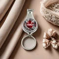 Detail view of a metal Canada flag nail clipper keychain on a soft fabric background - Style 19