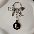 Detail of silver stethoscope keychain with nurse cap, syringe, and floral letter L charm - L