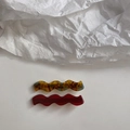 Macro shot of wave-shaped cellulose acetate hair clips in tortoiseshell and ruby red - Amber Tortoise / Dark Red