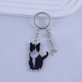 Detail of cartoon resin cat keychain with fishbone charm and silver key ring attachment - Black and White Cow Cat Style