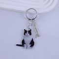 Detailed view of black and white tuxedo cat resin keychain with silver fishbone charm - Sitting Cow Cat Style