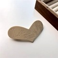 Vista macro di un fermaglio per capelli a cuore crema con incisione e finitura opaca - Caffellatte