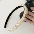 Nahaufnahme des beigefarbenen Tweed-Stirnbands mit Goldfäden und kleinem ovalem Logo - Hellgelb