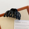 Close-up of a large matte black hair claw clip with sleek curved lines on a vintage card - Black (B-2872-2)