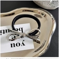 Elegant black hair tie with silver metallic bow detail on a stylish silver tray - Silver Bow Hair Tie Elastic