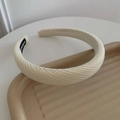 Cremeweißes dickes Strickstirnband mit handgefertigtem Label auf gewelltem Tablett - Gebrochenes Weiß