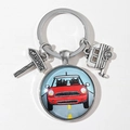 Macro view of camping keychain featuring cartoon red car pendant and camper charm - Orange Red