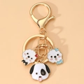 Dettaglio di un portachiavi dorato in lega con tre simpatici ciondoli a forma di cane in smalto - Stile Cane Accessorio Rosa (3)