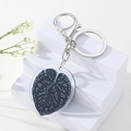 Blauer Blatt-Acryl-Schlüsselanhänger mit Silberclip auf weißem Ständer mit Blumen - Blau Gefleckt Blattform Stil