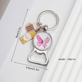 Detalle del llavero de mariposa vintage con abridor de botellas y colgantes de cerveza - Mariposa Rosa