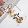 Detail of cow keychain with sunflower motifs, yellow tassel, and rainbow charm accessories - Cow & Sunflower Pattern (Style 2)