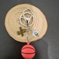 3D basketbal sleutelhanger met rode bal en zilveren ring op een rustieke houten schijf - Basketbalstijl