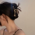 Elegante pinza per capelli in metallo dorato a forma di freccia su un'acconciatura a chignon - Oro