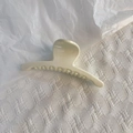 Minimalist cream white hair claw clip with glossy finish on soft textured fabric background - White