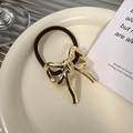 Nahaufnahme der goldenen Metallschleife auf dem braunen elastischen Haargummi im Tablett - Goldene Schleife (D-4976-2)