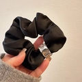 Gros plan détaillé du chouchou en satin noir avec un ornement rectangulaire brillant - Noir