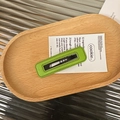 Close-up of a rectangular grass green leather hair clip with lychee texture in a wooden tray - Green