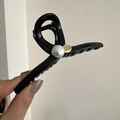 Dettaglio della molletta per capelli nera lucida con perla e ciondolo dorato motivante - Nero