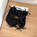 Detail of black silk satin hair scrunchie with delicate ribbon bows on wooden desk - Black