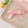 Dettaglio della clip per capelli con fiocco a quadretti rosa su vassoio in ceramica - Rosa