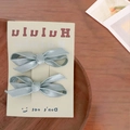 Detail of two dusty blue satin ribbon bow hair clips displayed on a minimalist card - Blue
