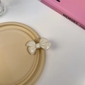 Vue détaillée d'une pince à cheveux nœud blanc crème avec finition brillante sur plateau - Barrette Blanche