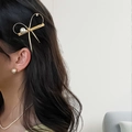 Elegante pasador de pelo de metal dorado con lazo y perlas usado en el lateral del cabello - Dorado
