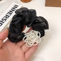 Dettaglio di scrunchie in organza nera con elegante fiore di perle per acconciatura ballet - Nero