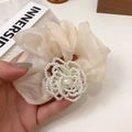 Dettaglio dell'elastico in organza color crema con un grande fiore di perle decorativo - Beige