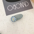 Detalle de una pinza para el pelo de resina gris con pequeña margarita azul sobre terrazo - Estilo Margarita Gris Azulado (D-5307-3)