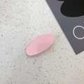 Macro detail of a pink matte oval hair clip with silver metal base on terrazzo - Pink