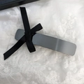Dettaglio di fermaglio per capelli vintage con fiocco e finitura opaca su pizzo bianco - Stile Canna di Fucile Nero Minimalista (D-5317-1)