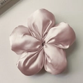Dettaglio macro dell'elastico per capelli a fiore in raso rosa cipria lucido - Rosa