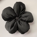 Dettaglio ravvicinato di un elastico per capelli a fiore 3D nero in morbido raso di lusso - Nero