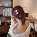 Detail von rosa Tweed-Haarklammern mit schwarzen Schleifen getragen von einem Modell - Rosa
