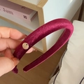 Vista detallada de la diadema de terciopelo burdeos con una pequeña placa de logo dorada redonda - Estilo Rojo Vino (D-4512-4)