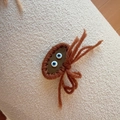 Detailed macro view of a handmade brown knitted crab hair clip with quirky blue eyes - Dark Brown Crab Style (D-5656-4)