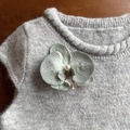 Elegante molletta orchidea verde con perla fissata su un maglione di maglia grigio - Grigio