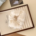 Elegant white pleated scrunchie with feather fringe detail on a jewelry tray - Beige