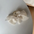 Elegant large beige chiffon bow hair claw clip for French style updos on grey table - Off-white