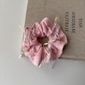 Roze gebreide haarelastiek met witte lintstrikken op een boek voor haarstyling - Roze