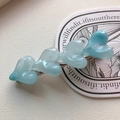 Detail shot of four blue heart-shaped resin charms on a silver metal hair clip - Blue