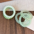 Macro shot of green spiral phone cord hair ties with matte, glitter, and floral patterns - Green Series Spiral Hair Rings