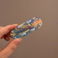 Détail d'une pince à cheveux en résine avec rubans tressés bleu jaune et orange - Vert