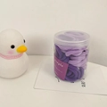 Close-up of elastic hair ties in purple shades organized in a transparent storage jar - Purple