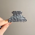 Dettaglio della grande pinza per capelli a scacchi bianchi e neri con finitura lucida - Grande